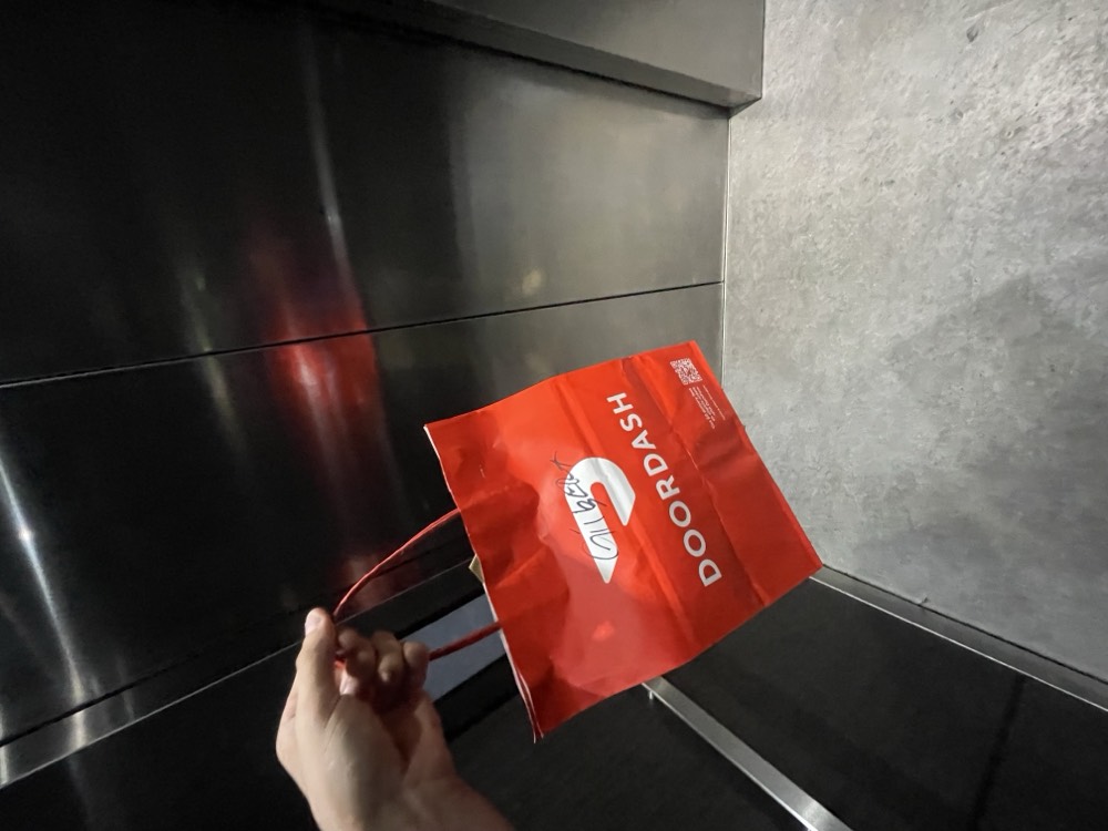 DoorDash order being carried through an apartment elevator