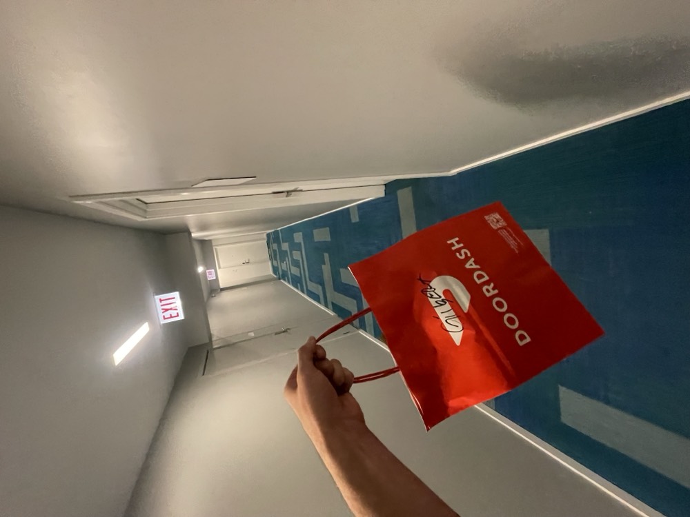 DoorDash order being carried down an apartment hallway